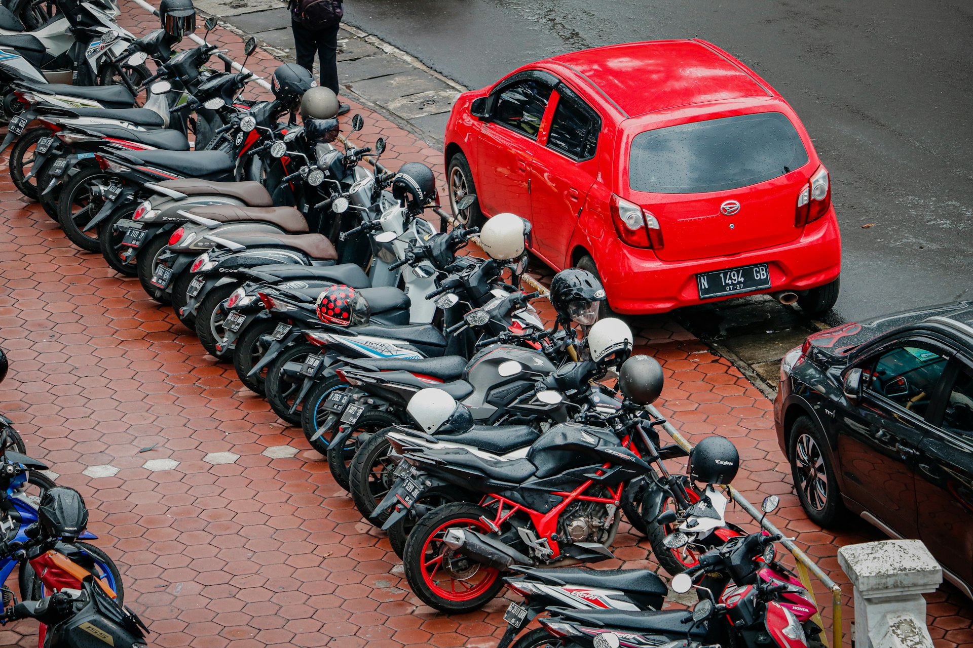 a row of motorcycles parked next to a red car